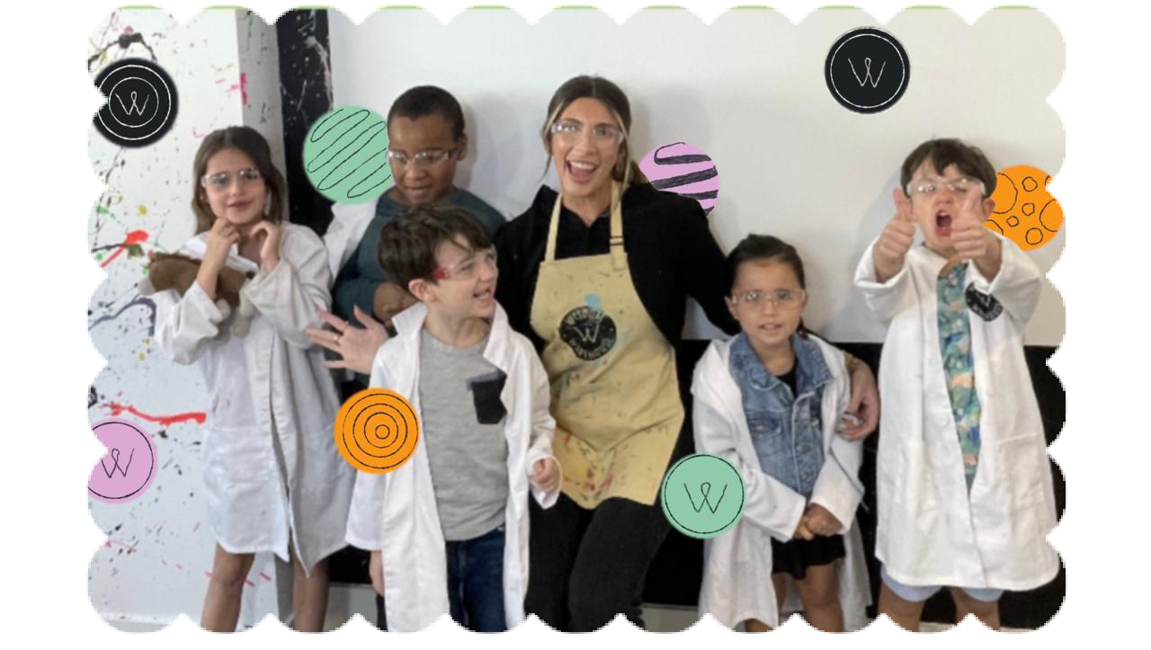 Students and teacher in lab coats at Wisdom Warehouse